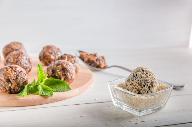 Nourriture végétarienne, boules d'énergie maison de noix, dattes, pruneaux, canneberges et miel au sésame sur fond blanc