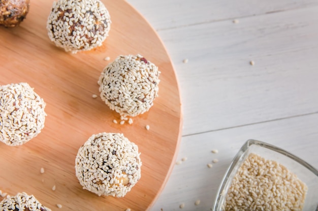 Nourriture végétarienne, boules d'énergie maison de noix, dattes, pruneaux, canneberges et miel au sésame sur fond blanc