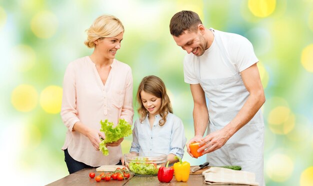 Nourriture végétarienne, culinaire, bonheur et concept de personnes - salade de légumes de cuisine familiale heureuse pour le dîner dans la cuisine à domicile fond de feux verts