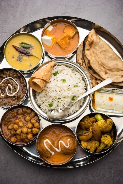 La nourriture végétarienne indienne Thali ou plateau comprend du beurre de paneer masala, dal makhani ou tarka, chole papad, kofta curry, gulab jamun, aloo-gobi sabji, chapati et riz avec bengali sucré servi