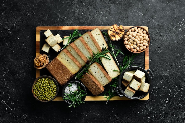 Nourriture végétarienne Tofu fromage au romarin coupé en morceaux sur une planche Sur un fond de pierre