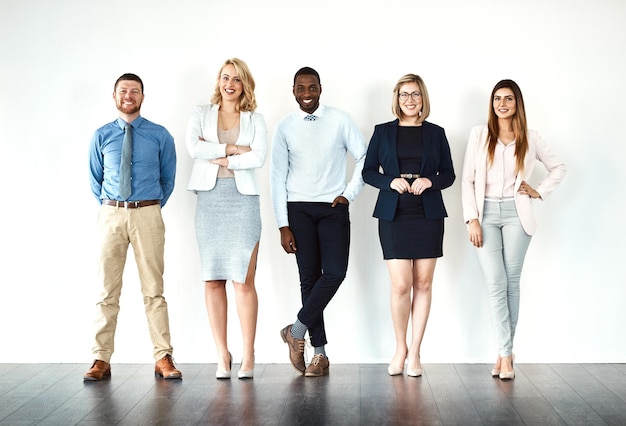 Nous appelons les plans Portrait d'un groupe de collègues de travail faisant la queue tout en utilisant leurs appareils sans fil sur un fond blanc