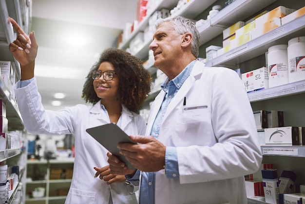 Nous avons besoin de plus de ces médicaments Plan de deux pharmaciens concentrés se promenant et faisant le stock à l'intérieur d'une pharmacie