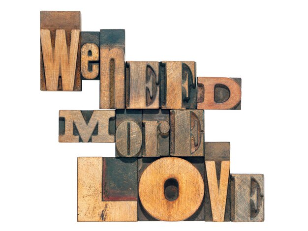 Photo nous avons besoin de plus de phrases d'amour faites à partir de caractères de presse en bois mélangé isolé sur blanc