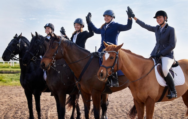 Nous l'avons fait Photo recadrée d'un groupe de jolies jeunes femmes jockeys qui font la fête tout en étant assises sur le dos de leur cheval