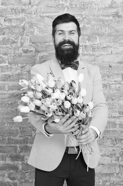 Nous créons des émotions Homme barbu avec bouquet de tulipes Date d'amour vacances internationales Journée de la femme Fleur pour le 8 mars Cadeau de printemps Homme barbu hipster avec des fleurs émotions heureuses homme de printemps heureux