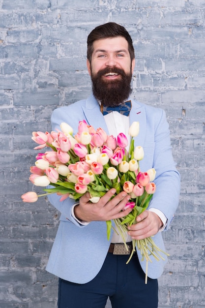 Nous créons des émotions. Homme barbu avec bouquet de tulipes. Rendez-vous amoureux. jour férié international. Journée de la femme. Fleur pour le 8 mars. Cadeau de printemps. Hipster barbu avec des fleurs. émotions heureuses. homme de printemps heureux.