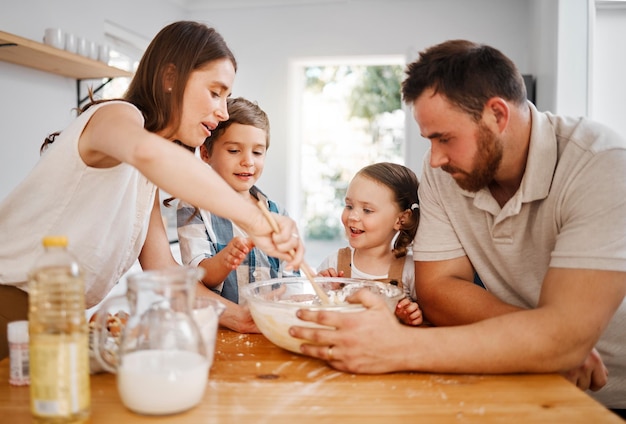 Nous n'aurons certainement pas de cookies achetés en magasin aujourd'hui. Plan d'un couple et de leurs deux enfants cuisinant ensemble à la maison.