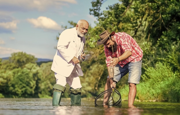 Nous sommes une famille concept de capture et de pêche papa à la retraite et fils barbu mature amitié de pêcheurs heureux Deux amis masculins pêchant ensemble poisson à la mouche passe-temps de la pêche à la retraite