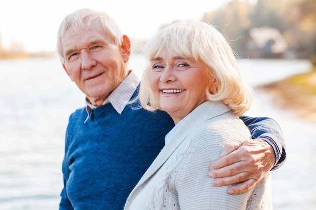 Nous sommes heureux ensemble. Heureux couple de personnes âgées se liant et souriant tout en se tenant ensemble sur le quai