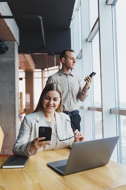 Nous travaillons ensemble sur un projet d'entreprise Deux jeunes collègues d'affaires travaillent sur un ordinateur portable dans un grand bureau moderne Partenariat de relations d'affaires