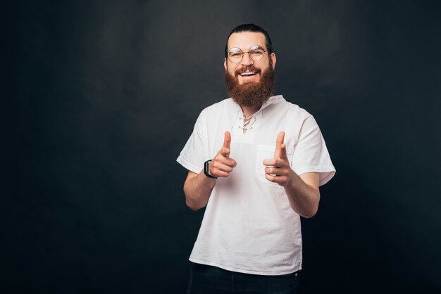 Nous vous voulons pour ce travail. L'homme barbu pointe vers la caméra avec les deux mains.