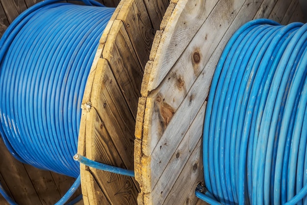 Le nouveau câble d'alimentation bleu est enroulé sur une bobine en bois Câble d'arrière-plan pour la pose souterraine