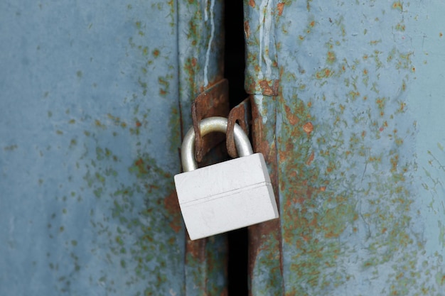 Nouveau cadenas fermé sur une vieille porte métallique