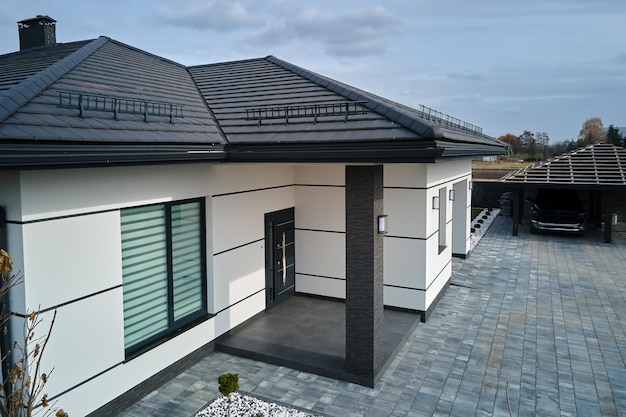 Nouveau chalet de maison d'habitation et garage attenant avec grande cour pavée clôturée par une journée ensoleillée dans la banlieue moderne Concept de propriété immobilière