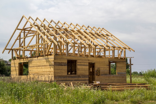 Nouveau chalet de matériaux de bois naturel écologique en construction dans un champ vert. Murs en bois et charpente raide. Propriété, investissement, construction professionnelle et concept de reconstruction.