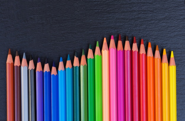 De nouveau à la frontière d'arc-en-ciel de crayons d'école sur le fond noir