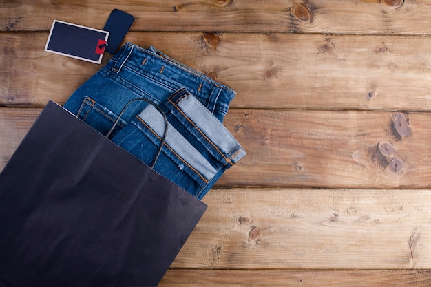 Nouveau jean dans un sac noir sur un bois marron