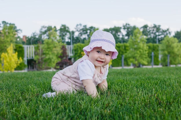 nouveau-né allaitant bébé fille assise sur l'herbe dans le parc et souriant par une journée ensoleillée d'été