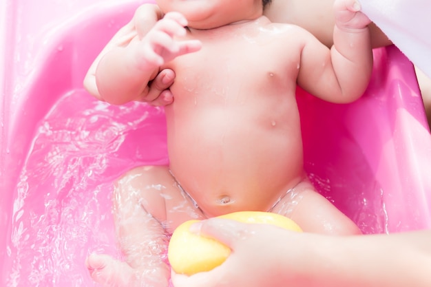 Photo nouveau-né asiatique ayant un bain dans le bassin de ping par une nouvelle mère