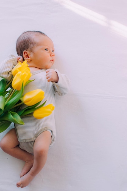 Un nouveau-né avec un bouquet de tulipes 8 mars Bébé et fleurs Tulipes jaunes