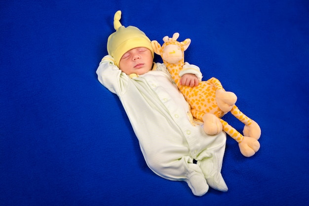 Nouveau-né couché sur une couverture bleue avec girafe jouet. Garçon ou fille