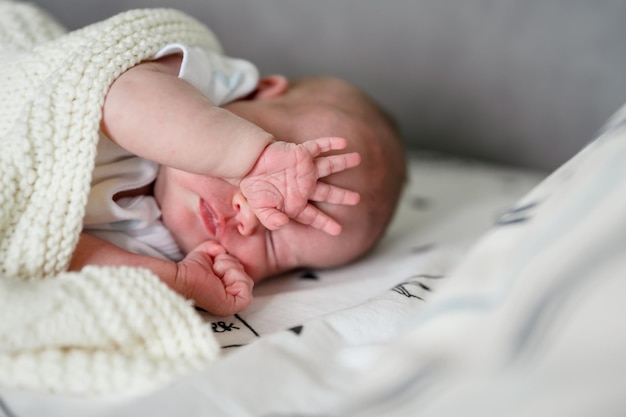 Un nouveau-né couvre son visage avec sa main