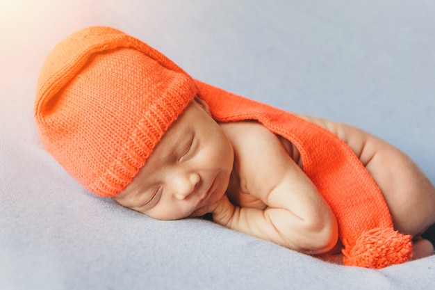 Le nouveau-né dort avec un chapeau orange