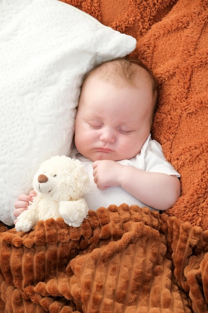 Un nouveau-né dort sur un lit Un ours en peluche se trouve à proximité de la mère et de l'enfant