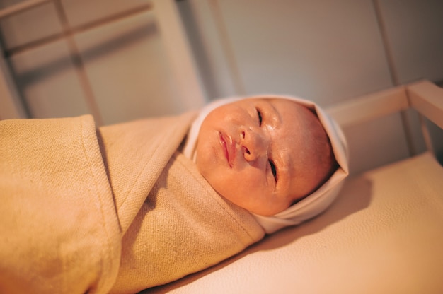 Un nouveau-né enveloppé après la naissance se trouve sur la table.