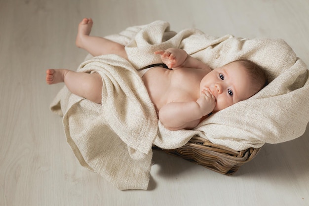 Le nouveau-né enveloppé dans une couverture en lin se trouve dans un berceau en osier. produits pour enfants. concept de sommeil sain et de développement de l'enfant. enfance et maternité heureuses. Photo de haute qualité