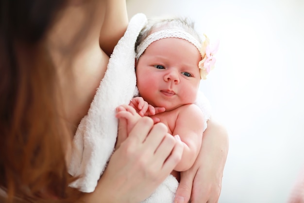 Un nouveau-né est allongé dans les bras de sa mère. Un beau bébé d'apparence européenne dort.