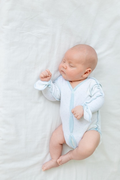 Un nouveau-né garçon dort sept jours dans un lit bébé à la maison sur une vue de dessus de lit en coton