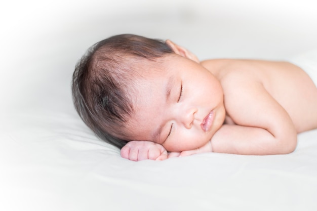 Nouveau-né mignon dort sur un lit blanc