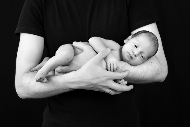 Un nouveau-né repose dans les mains de papa.