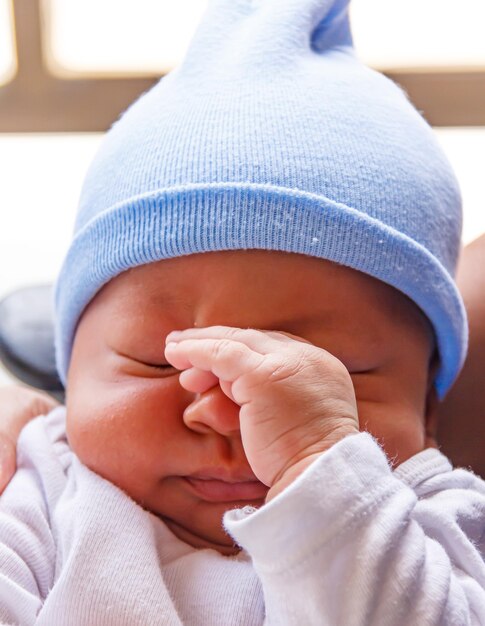 Photo un nouveau-né se touche le visage avec ses mains.