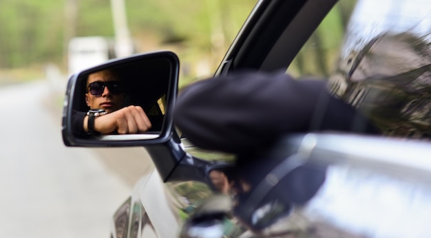 Nouveau point de vue Guy drive automobile Conducteur vu dans le rétroviseur de voiture Rétroviseur latéral ou arrière Reflet miroir d'un bel homme Transport et transport Voyage de vacances Aventure et découverte