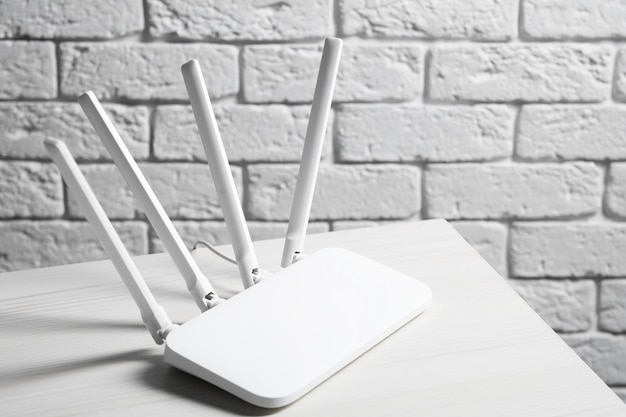 Photo nouveau routeur wifi sur une table en bois blanc contre un mur de briques espace pour le texte