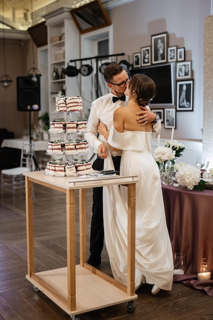 Les nouveaux mariés coupent joyeusement le rire et goûtent le gâteau de mariage