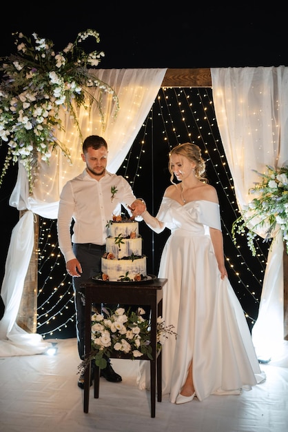 Les nouveaux mariés coupent joyeusement le rire et goûtent le gâteau de mariage