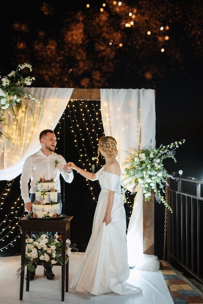 Les nouveaux mariés coupent joyeusement le rire et goûtent le gâteau de mariage