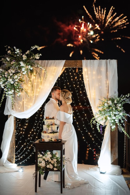 Les nouveaux mariés coupent joyeusement le rire et goûtent le gâteau de mariage