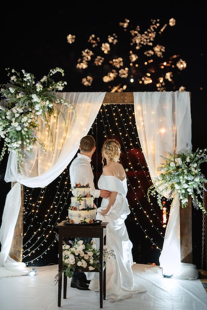 Les nouveaux mariés coupent joyeusement le rire et goûtent le gâteau de mariage