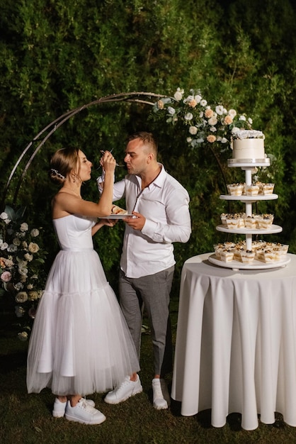 Les nouveaux mariés coupent joyeusement le rire et goûtent le gâteau de mariage