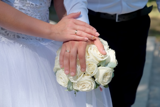 Les nouveaux mariés mettent la main sur le bouquet. Vue rapprochée