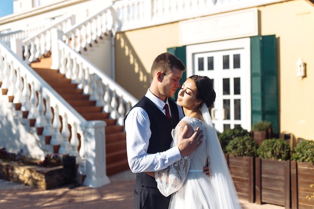 Les nouveaux mariés s'embrassent tendrement et s'amusent Marche des amoureux Incroyable couple de mariage souriant