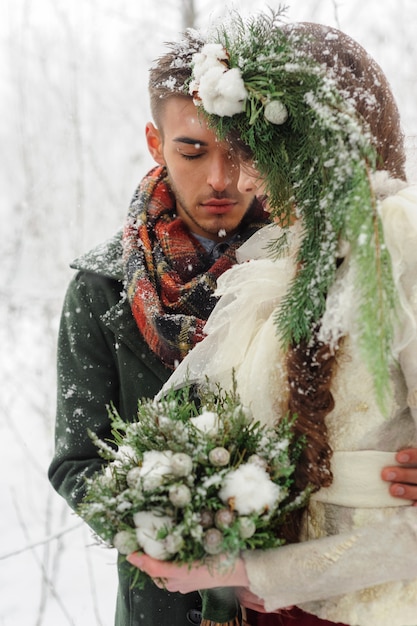 Les nouveaux mariés se serrent dans la forêt d'hiver. Couple amoureux. Cérémonie de mariage d'hiver.