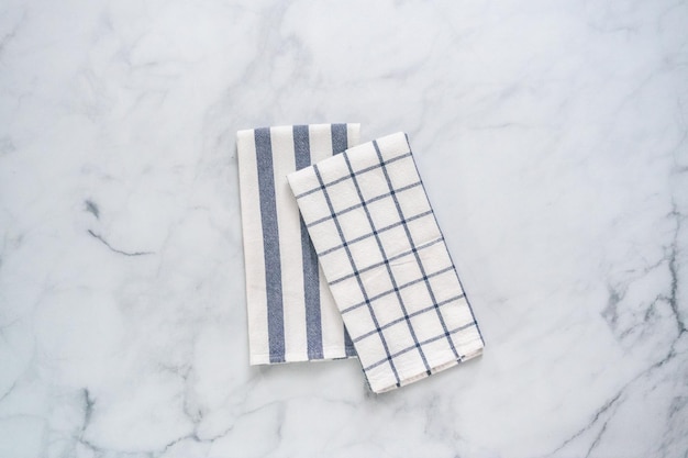 Nouveaux torchons de cuisine avec un motif bleu simple plié sur un comptoir en marbre.