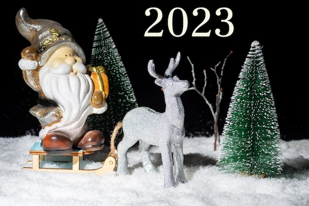 Nouvel An 2023 Un cerf argenté brillant jouet portant un traîneau avec le Père Noël avec des cadeaux à travers la forêt enneigée