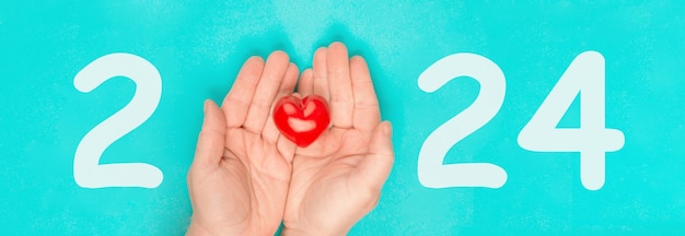 Nouvel an 2024 calendrier date coeur rouge dans la paume des mains concept caritatif nouveaux objectifs